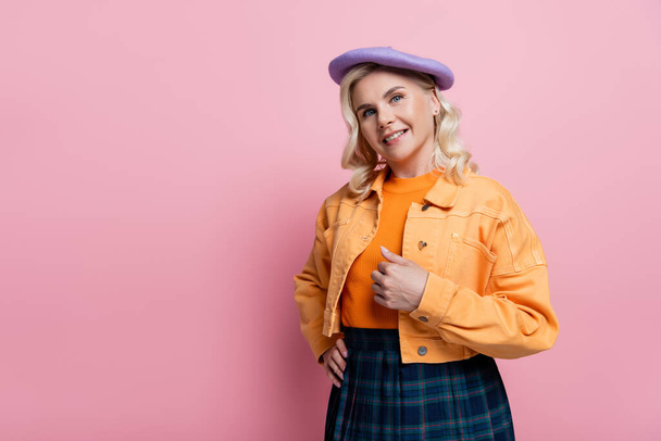 Stylish woman in beret holding hand on hip on pink background - Foto, immagini
