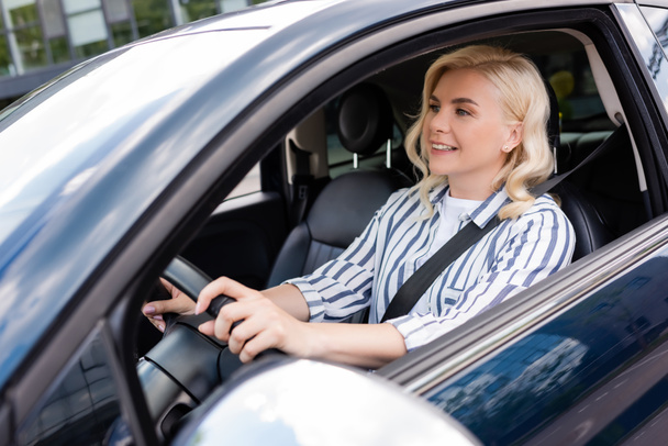 Cheerful woman looking away during driving courses in car  - Foto, Imagen
