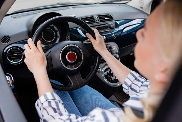 Blurred woman holding steering wheel of car during driving course  - Foto, Imagen