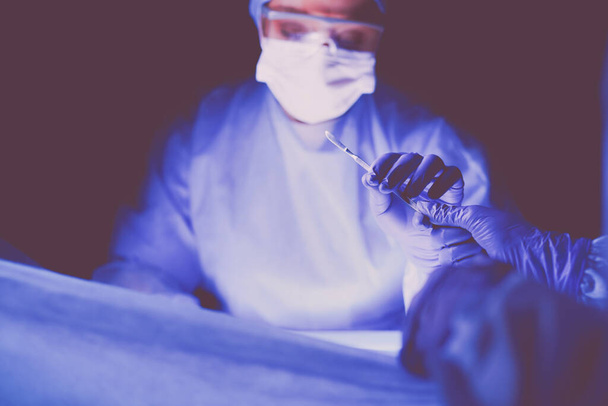 Doctor performing surgery in a dark background - Fotografie, Obrázek
