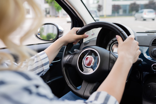 Cropped view of blonde driver holding steering wheel of car  - Foto, Imagen