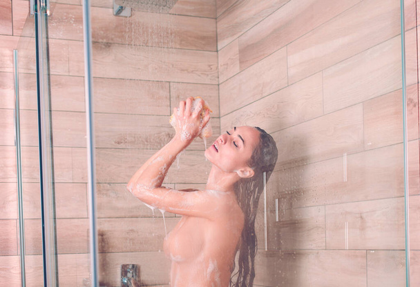 Young beautyful woman under shower in bathroom - Fotó, kép