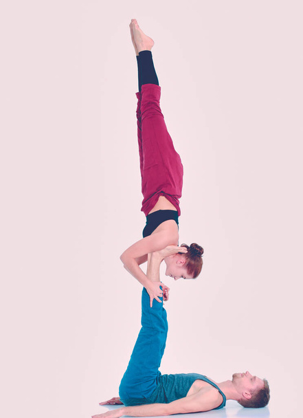 Young athletic couple practicing acroyoga. Balancing in pair - Фото, изображение