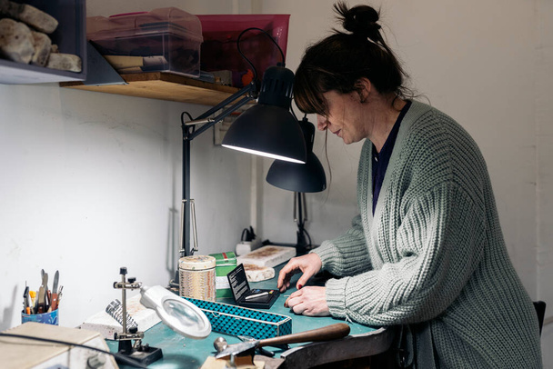 Focused adult craftswoman working in jewelry atelier. - Foto, Imagen