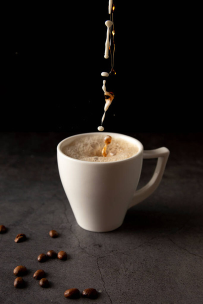 Filling a coffee cup with coffee and milk in slow motion on a concrete background - Foto, immagini