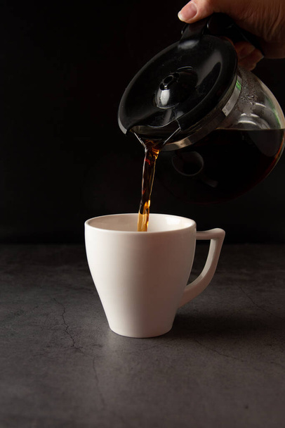Filling a coffee cup with coffee in slow motion on a concrete background - Foto, Imagem