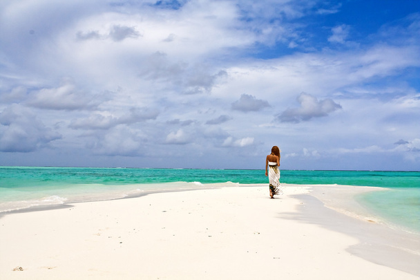 Beautiful view of slender young woman walking alone on ocean beach - Photo, Image