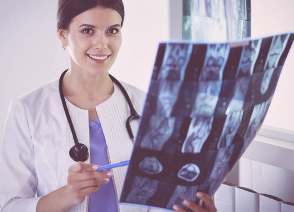Young smiling female doctor with stethoscope holding X-ray at doctors office - Fotó, kép