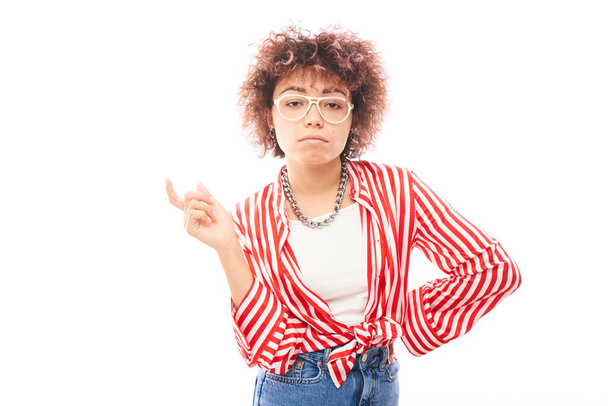 Positive kazakh girl with afro hairstyle points forefinger at copy space isolated on white studio background - Foto, Bild