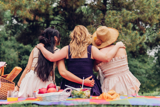 Rear view of a group of unrecognizable female friends, enjoying a picnic with vegan and healthy food outdoors during a trip. - Foto, Imagem