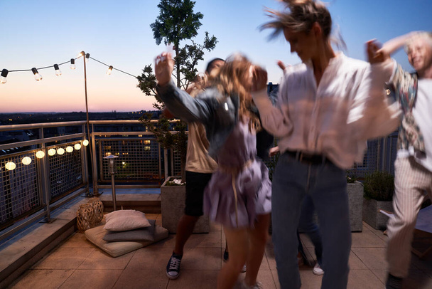 Group of friends dancing at the rooftop party in the evening  - Foto, immagini
