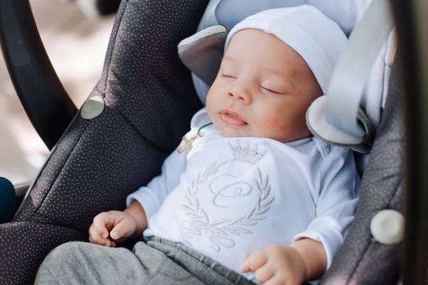 baby sleeping in a car seat with a crown pattern on clothes princes - Foto, Imagem