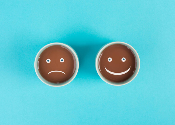 Чашка кави з сумним та щасливим обличчям, позитивним та негативним мисленням, концепцією підтримки та оцінки, емоціями
 - Фото, зображення