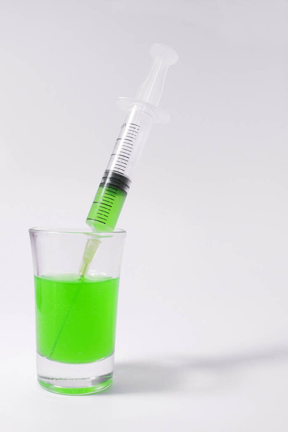 Syringe with green liquid on the white background. Syringe and glass on a white background.  - Foto, Imagen