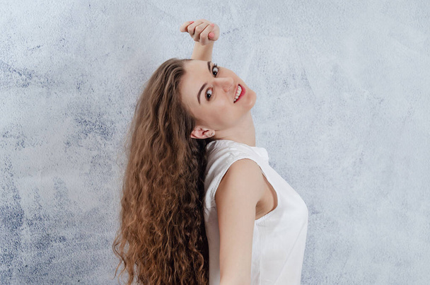 Portrait of charming young woman. Long curly dark hair. She threw her head back. Dazzling smile. White blouse - Foto, imagen