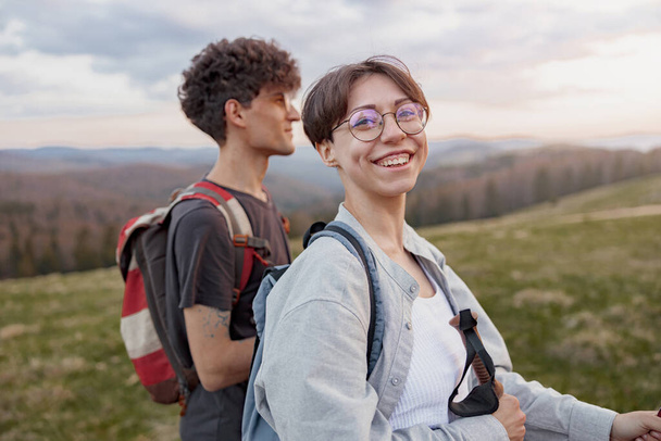Portrait of cheerful happy woman hiking with male friend or boyfriend by mountains. Trekking on tops - Zdjęcie, obraz
