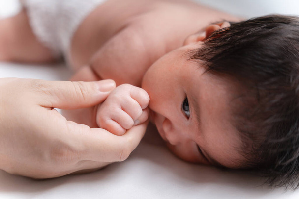 Asian Little newborn baby girl one month old. infant. hand the practicing development baby in the hand of mother close up, New family and baby protection from mom concept. - Foto, Imagen