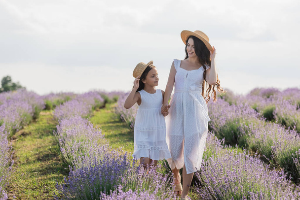 mom and child in white dresses walking and holding hands in field - Foto, Imagem
