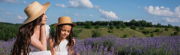 brunette woman in straw hat hugging daughter in lavender meadow, banner - Foto, Imagen