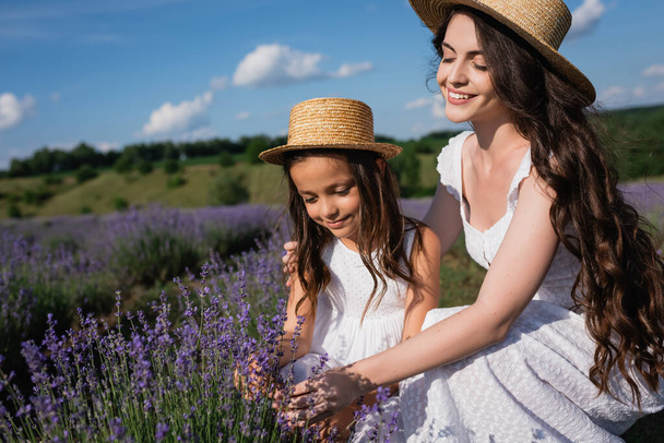 woman and child with long brunette hair near blossoming lavender in meadow - Foto, Imagen