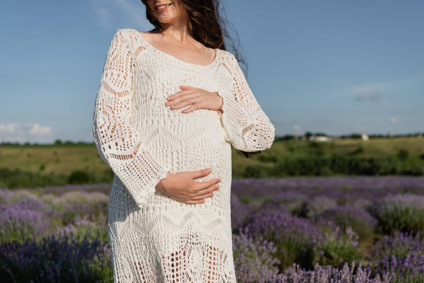 cropped view of pregnant woman in dress embracing tummy outdoors - Φωτογραφία, εικόνα