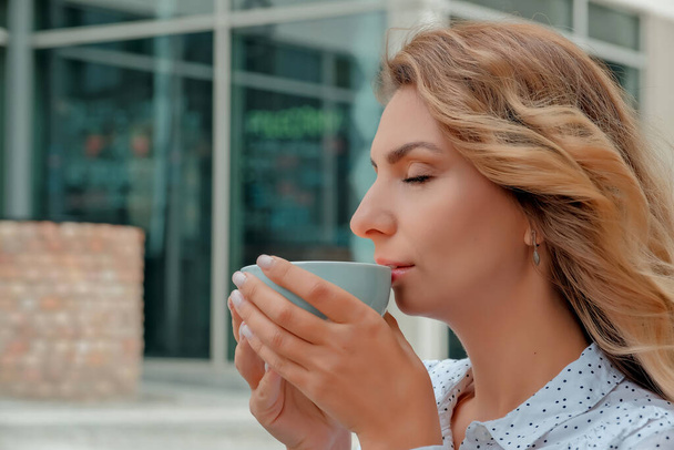 girl drinking coffee on the street. a cup of coffee. a cup of coffee and a girl's face close-up. - Фото, зображення