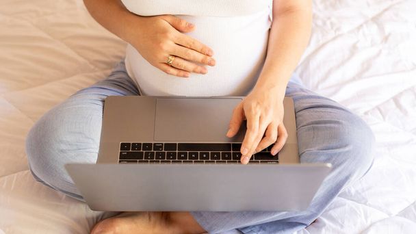 Έγκυος υπολογιστής. Έγκυος γυναίκα κρατά ψηφιακό φορητό υπολογιστή. Κινητή εγκυμοσύνη σε απευθείας σύνδεση εφαρμογή μητρότητας. Έννοια της εγκυμοσύνης, μητρότητας, προσδοκία για τη γέννηση του μωρού - Φωτογραφία, εικόνα