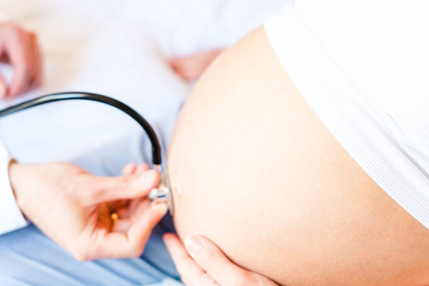 妊娠中の医者病院。妊娠コンサルタントのための医療クリニック。妊娠中の女性の腹を調べる医者は聴診器を持っている。妊娠,医学ヘルスケアの概念 - 写真・画像