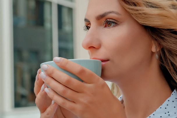 girl drinking coffee on the street. a cup of coffee. a cup of coffee and a girl's face close-up. - Foto, Imagem