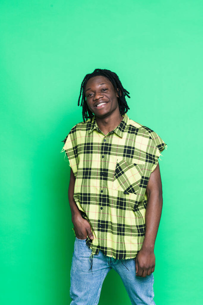 Young black man with dreadlocks smiling and looking at camera isolated over green background - Fotografie, Obrázek