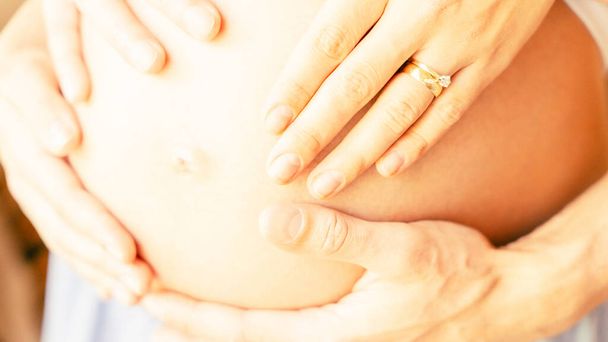 Zwangere handen vrouw buik. Gelukkige zwangere vrouw en man knuffelen zwangere buik. Concept moederschap, zwangerschap, bevalling - Foto, afbeelding