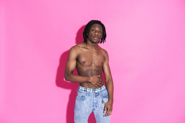 Black shirtless man with dreadlocks posing and looking at camera isolated over pink background - Foto, immagini