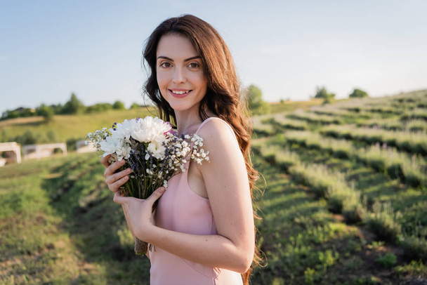happy woman holding bouquet of fresh flowers in meadow - Fotoğraf, Görsel