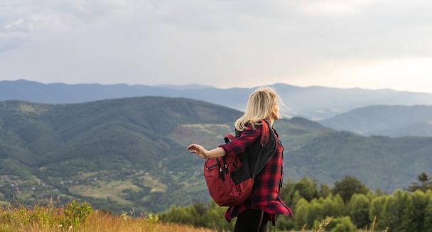 Красивая молодая женщина с рюкзаком ходит по лугу. Портрет туристки на открытом воздухе
. - Фото, изображение