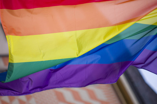 Közelkép szivárvány meleg büszkeség zászló kint az utcán. A Leszbikus Biszexuális Transznemű LMBT közösség jelképe, mely a szélben integet a felhős égbolttal szemben. Szociális mozgalom a szabadságért és az egyenlőségért. Fénymásolási tér  - Fotó, kép
