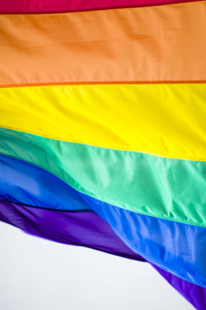 Bandiera dell'orgoglio gay dell'arcobaleno da vicino fuori su una strada. Simbolo della comunità LGBT transgender bisessuale lesbica che ondeggia nel vento contro il cielo nuvoloso. Movimento sociale per la libertà e l'equliaty. Copia spazio  - Foto, immagini