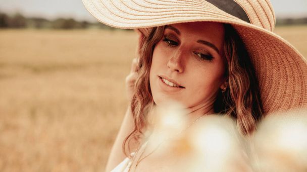 Κορίτσι καλοκαίρι χωράφι με σιτάρι. Ευτυχισμένη νεαρή γυναίκα με καπέλο στον καλοκαιρινό αγρό σιταριού στο ηλιοβασίλεμα. Φύση, καλοκαιρινές διακοπές, διακοπές και οι άνθρωποι έννοια - Φωτογραφία, εικόνα