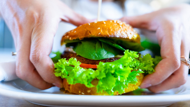 Vegan sandwich healthy vegetarian burger. Cute cheerful girl eating veggie hamburger with salad, avocado, vegetable. Vegetarian diet food concept - Fotografie, Obrázek