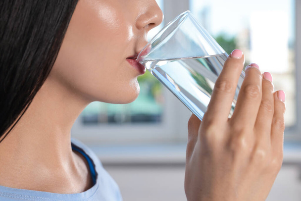 Young woman drinking water indoors, closeup. Refreshing drink - Photo, Image