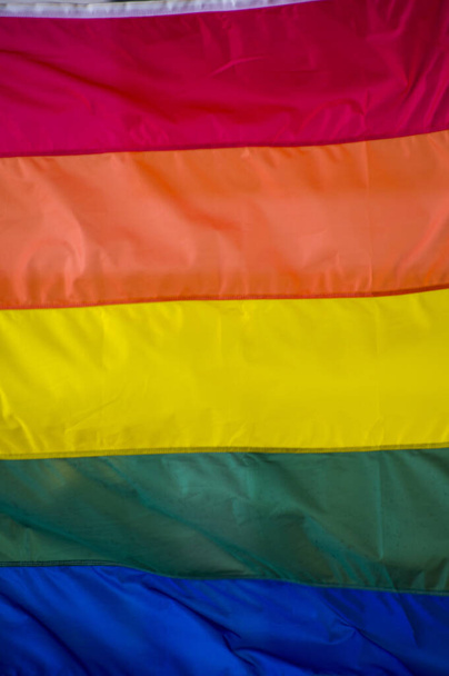 Close-Up rainbow gay pride flag outside on a street. Symbol of the Lesbian Bisexual Transgender LGBT community waving in wind against cloudy sky. Social movement for freedom and equliaty. Copy Space  - Foto, imagen