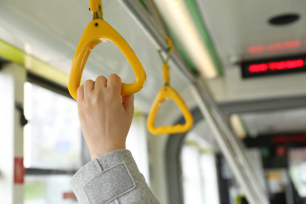 Woman holding handgrip handle in public transport, closeup - Foto, afbeelding