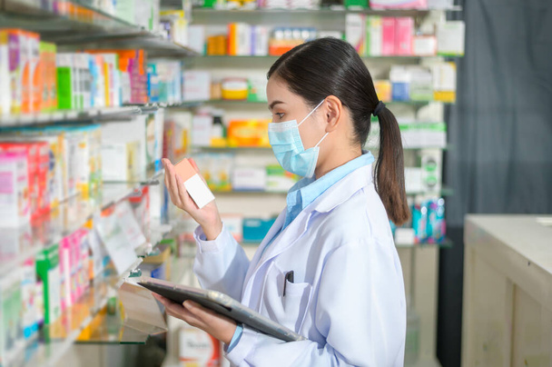A Portrait of female pharmacist wearing face mask in a modern pharmacy drugstore. - Foto, Imagem