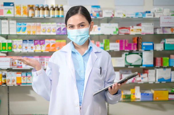 A Portrait of female pharmacist wearing face mask in a modern pharmacy drugstore. - Foto, immagini