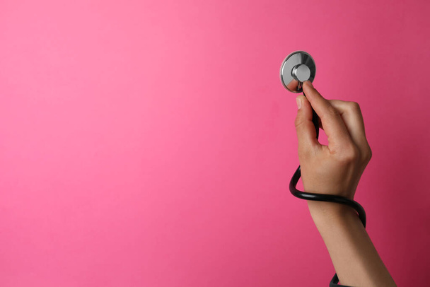 Woman holding stethoscope on pink background, closeup. Space for text - Fotografie, Obrázek