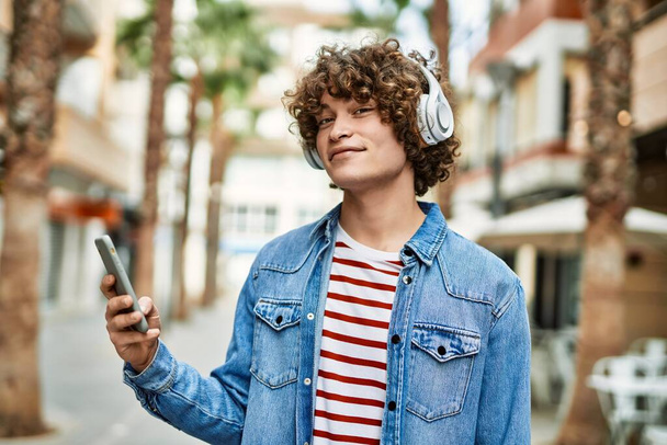 Young hispanic man listening to music from smartphone at the city - Photo, Image