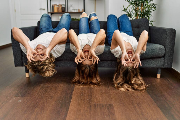 Mother and couple doing glasses gesture with hands lying on sofa at home - Foto, Bild