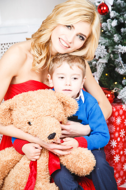 Portrait of beautiful blonde young woman with her little son over christmas background - Foto, immagini