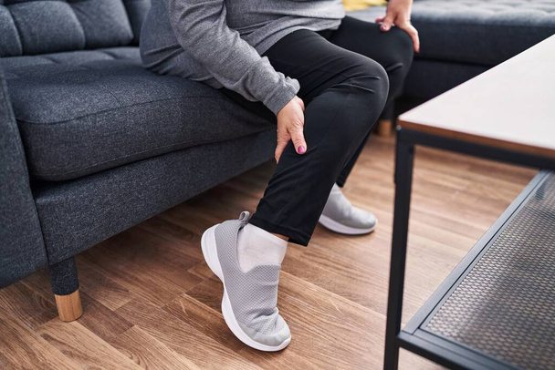Middle age blonde woman wearing sneaker sitting on sofa at home - Photo, Image