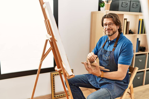 Homem caucasiano de meia idade sorrindo desenho confiante no estúdio de arte - Foto, Imagem