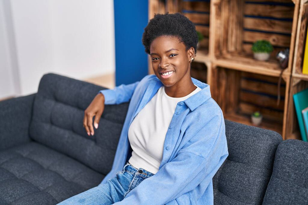 Африканська американка усміхається, коли сидить вдома на дивані. - Фото, зображення